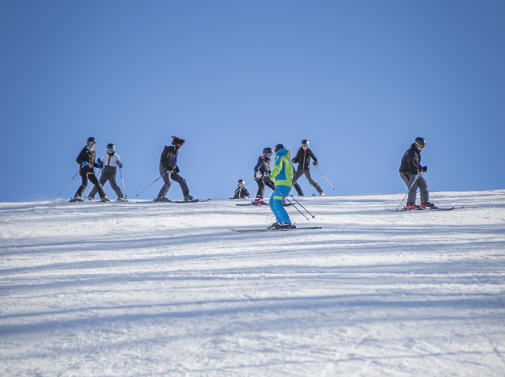 Instructor leading a group of adult skiers along a ridge