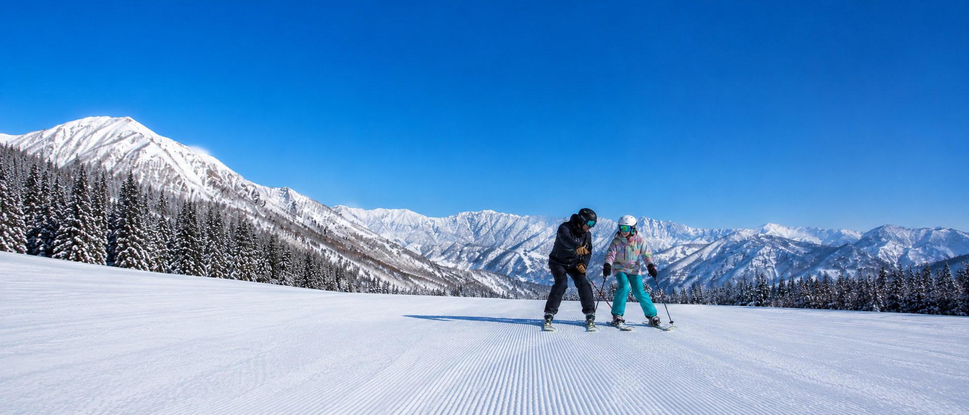 Instructor coaching a student on a groomed run below the Japanese Alps